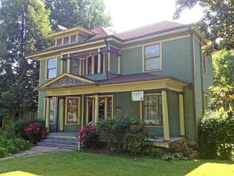 A restored two-story house with green clapboard siding and a deep front porch on St. Elmo Avenue in Chattanooga's St. Elmo neighborhood