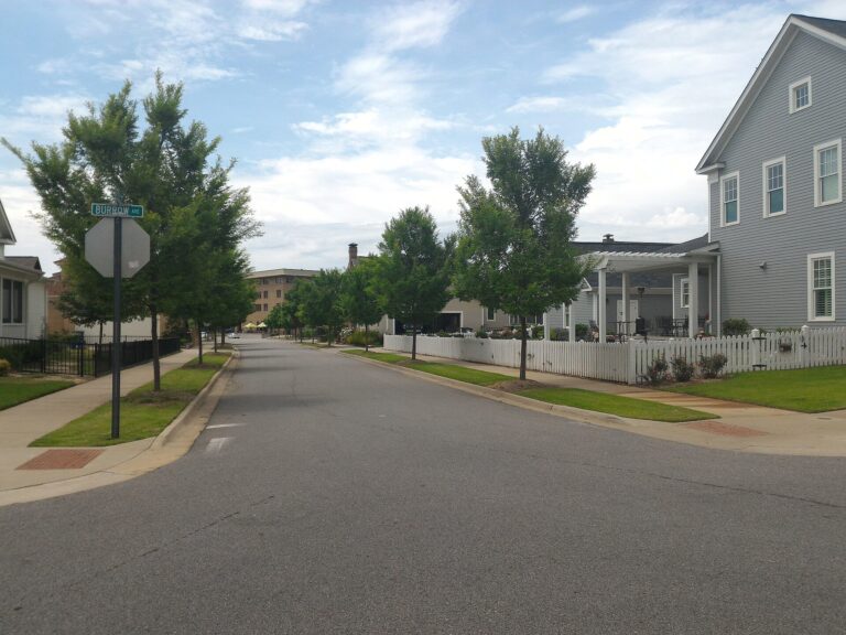 Residential street with sidewalks, young trees and a white picket fence in the Hendrix area of Conway, Arkansas