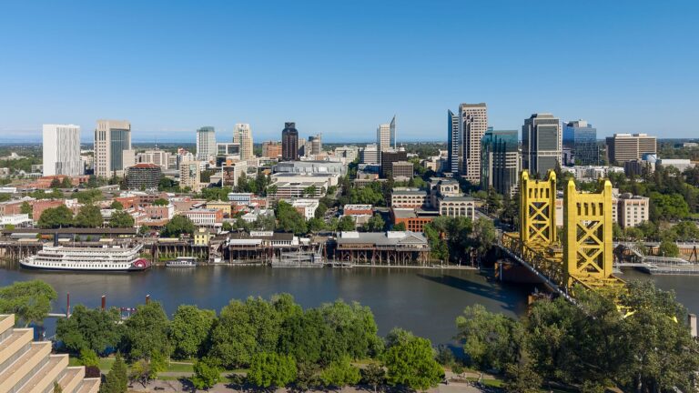 Downtown Sacramento skyline above the Sacramento River, with Old Sacramento's riverfront and the gold Tower Bridge