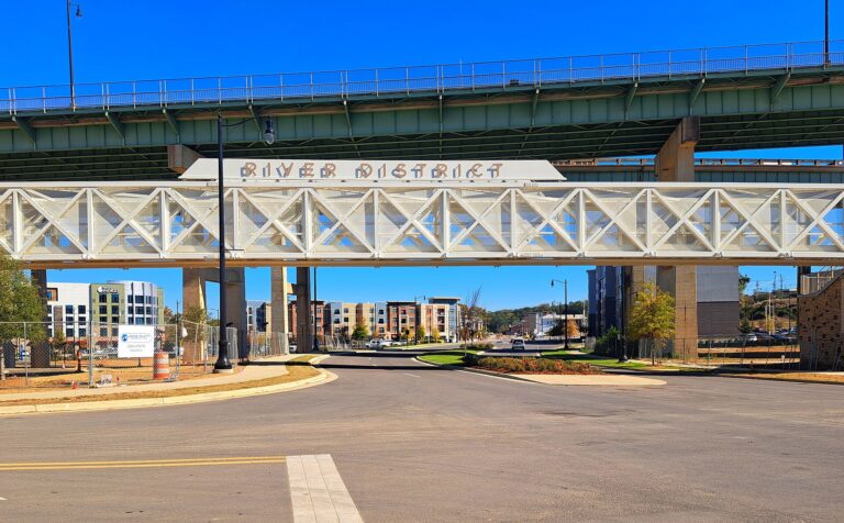 Street entering the River District in downtown Tuscaloosa, Alabama, with new apartment buildings beyond the pedestrian bridge
