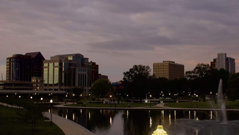 Downtown Huntsville, Alabama office buildings at dusk seen across the pond and fountains of Big Spring Park